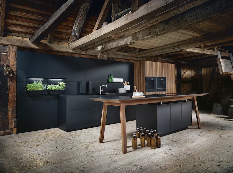 next125 zwarte keuken met Feniks fronten en werkblad. Kooktafel met onyx feniks blad en larix houten onderstel. Ook de hoge kasten hebben fronten van larix hout. De greeploze keuken met tip on heeft anti-fingerprint coating en next125 paneeltuinen met groeilampen voor het next125 Cube Systeem in onyx zwart #next125 #designkeuken #keuken #innovatie #eurocucina #eurocucina2018 